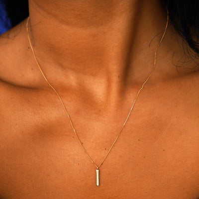 A model's neck wearing a solid yellow gold Bar Necklace