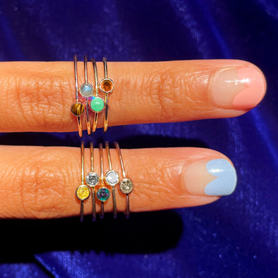 Two fingers with cool nail polish wearing various Automic Gold rings including a Jade Ring