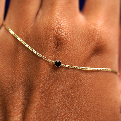 A solid gold Onyx Bracelet resting on the back of a model's hand