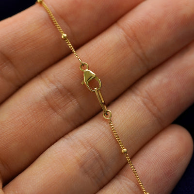 A model holding a gemstone evil eye bracelet to show the lobster claw clasp on the beaded essential chain
