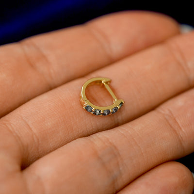 A small Alexandrite huggie hoop earring on a models fingers