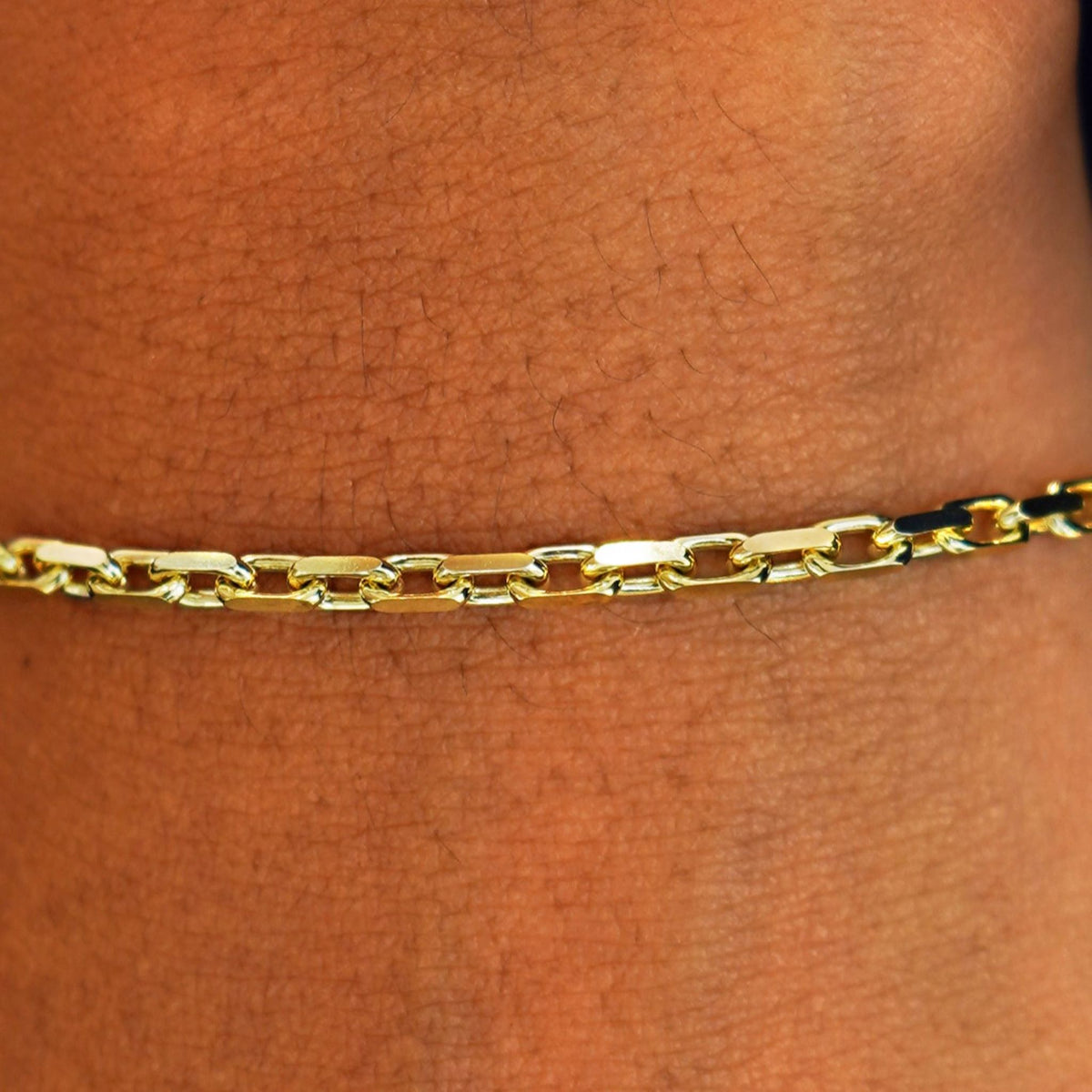Close up view of a model's wrist wearing a solid 14k yellow gold Anchor Bracelet