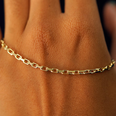 A solid gold Anchor Bracelet resting on the back of a model's hand