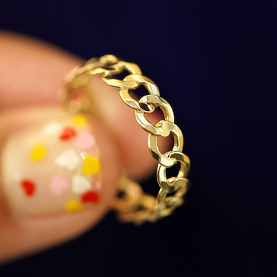 A model holding a yellow gold Curb Ring tilted to show the side of the ring