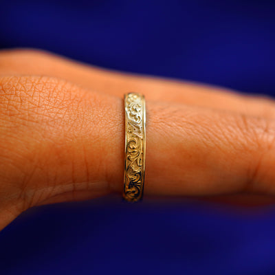 Side view of a model's finger wearing a yellow gold Filigree Band to show details