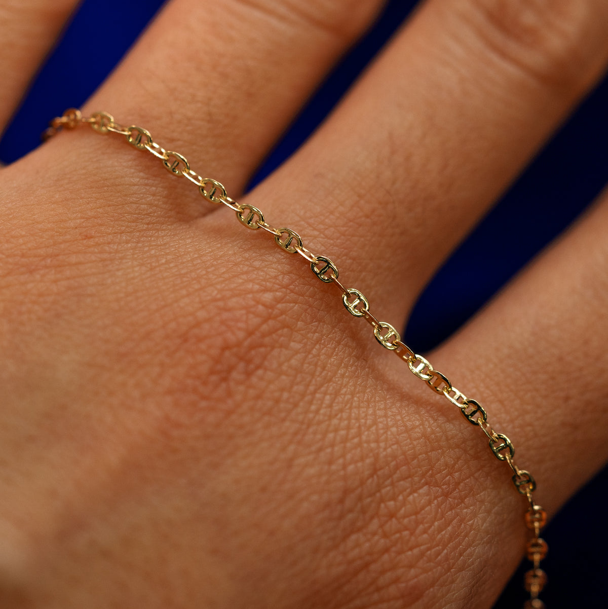 A yellow gold Flat Mariner Chain Necklace on the back of a model's hand to show the details of the links
