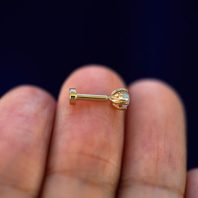 Side view of a yellow gold Opal Flatback Piercing on a model's fingertips