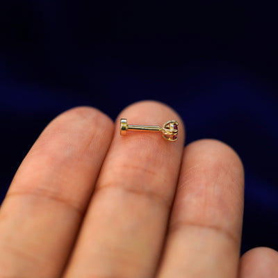 Side view of a yellow gold Ruby Flatback Piercing on a model's fingertips