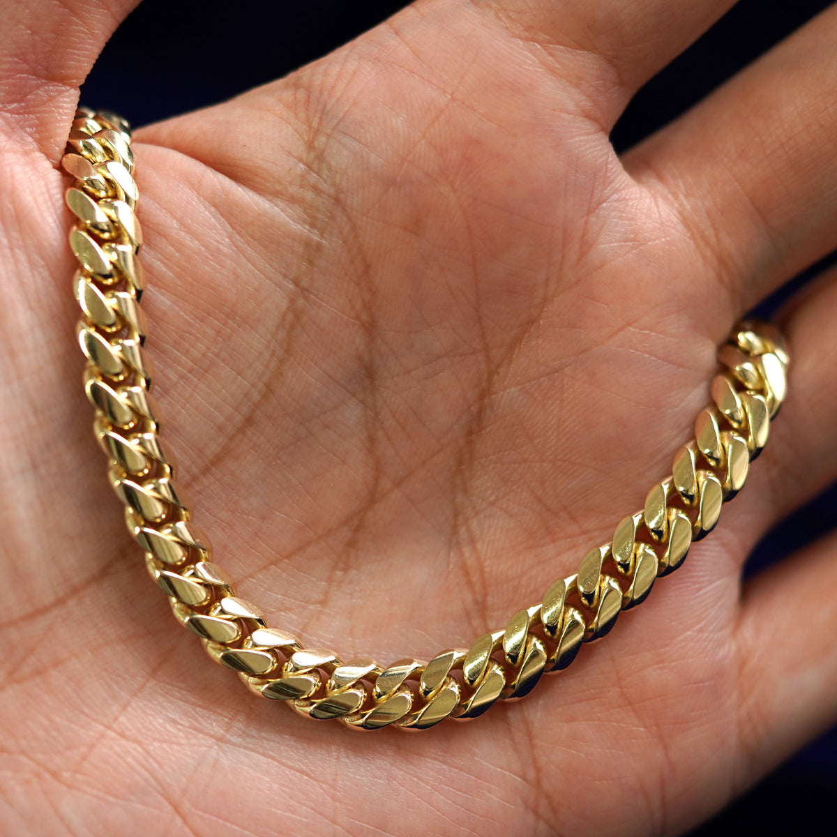 A yellow gold Miami Cuban Anklet draped on a model's palm