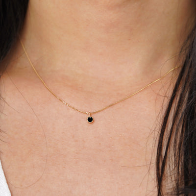 A model's neck wearing a solid 14k yellow gold Onyx necklace
