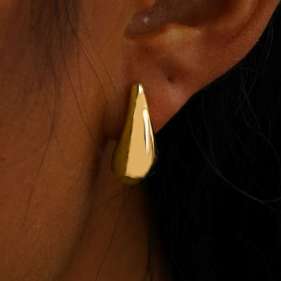 Close up view of a model's ear wearing a 14k yellow gold Teardrop Puffy Earring