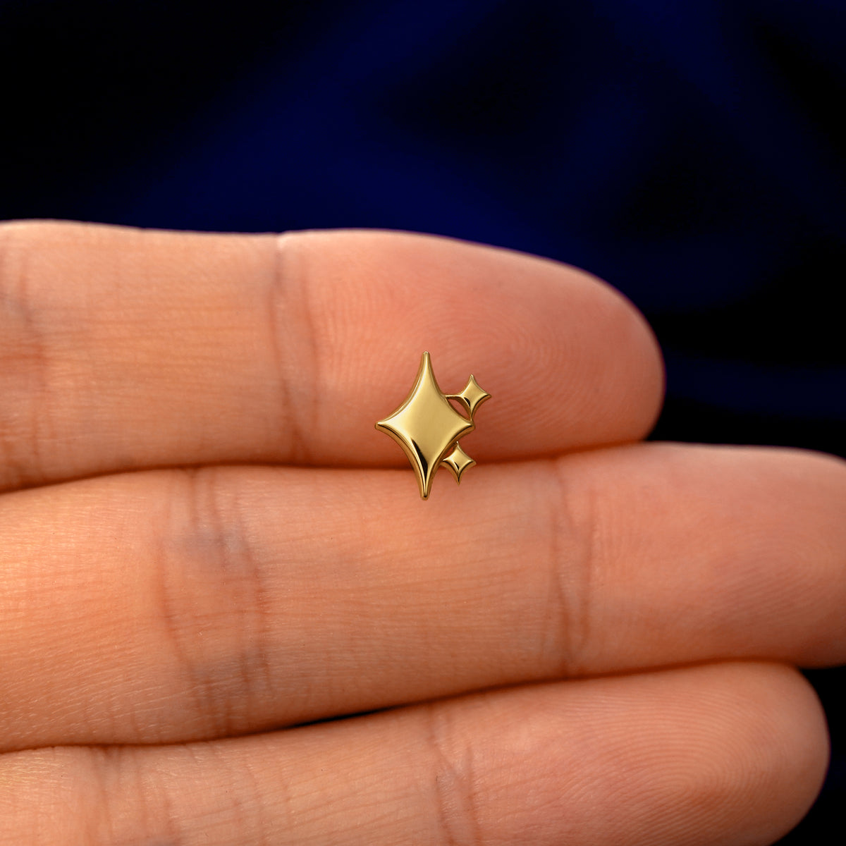 A model holding a solid gold Sparkly Emoji stud earring between two fingers