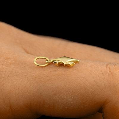 Side view of a 14k solid gold Sparkly Emoji Charm on a model's finger to show the details and thickness of the charm
