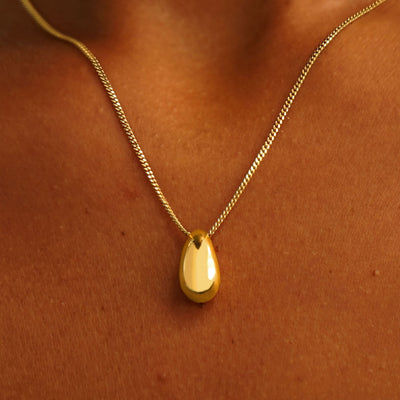 Close up view of a model's neck wearing a 14k yellow gold Puffy Teardrop Necklace