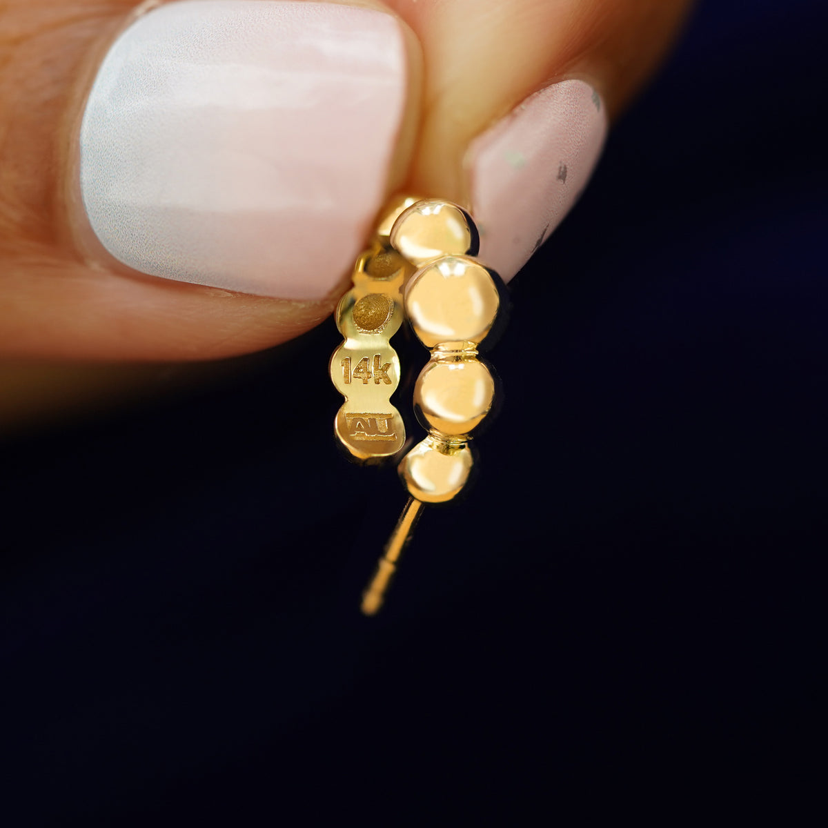 A Graduated Puffy Beaded Hoop held between a model's fingers to show the underside view of the hoop