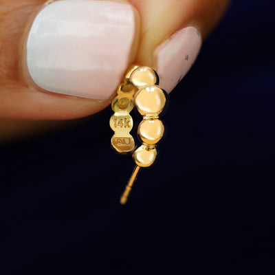 A Graduated Puffy Beaded Hoop held between a model's fingers to show the underside view of the hoop