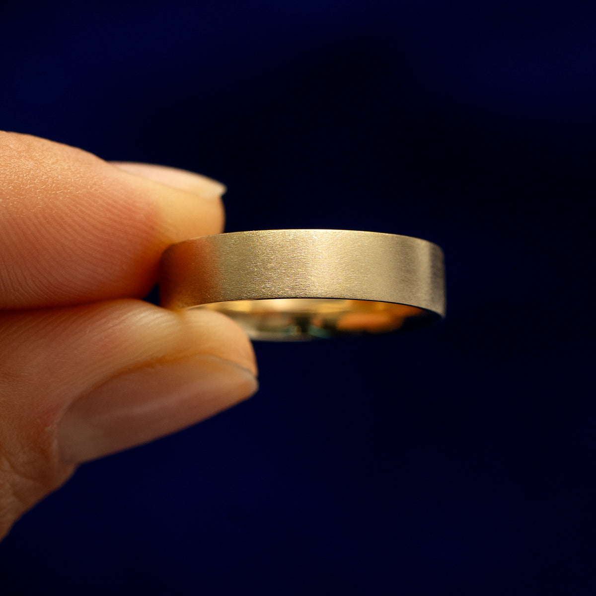 A model holding a Industrial Matte Band tilted to show the side of the ring