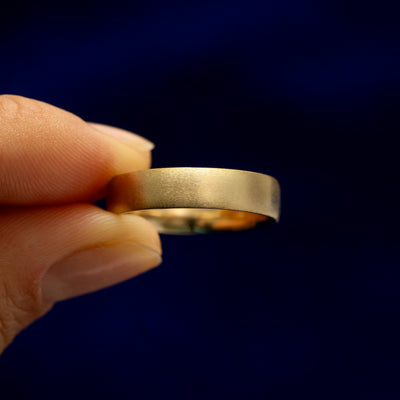 A model holding a 14k gold Mix Matte Band tilted to show the side of the ring