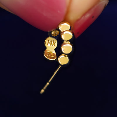 A Mini Puffy Beaded Hoop held between a model's fingers to show the underside view of the hoop