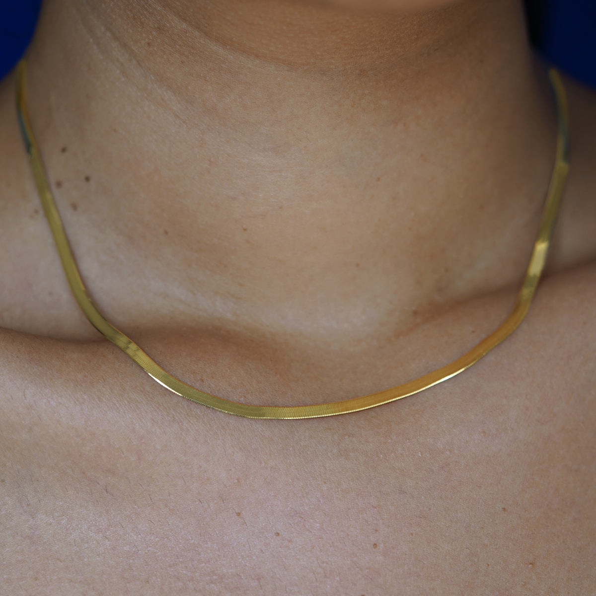 Close up view of a models neck wearing a custom 14k yellow gold Herringbone Chain Necklace