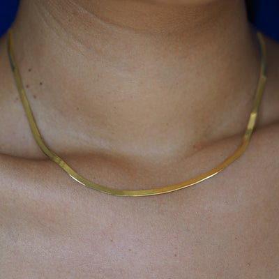 Close up view of a models neck wearing a custom 14k yellow gold Herringbone Chain Necklace