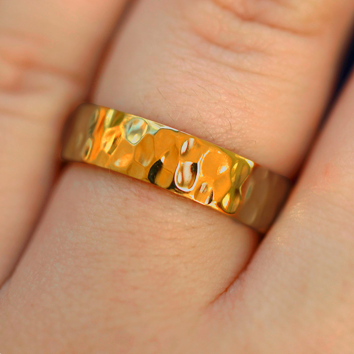 Close up view of a model's fingers wearing a 24k Band with a hammered finish