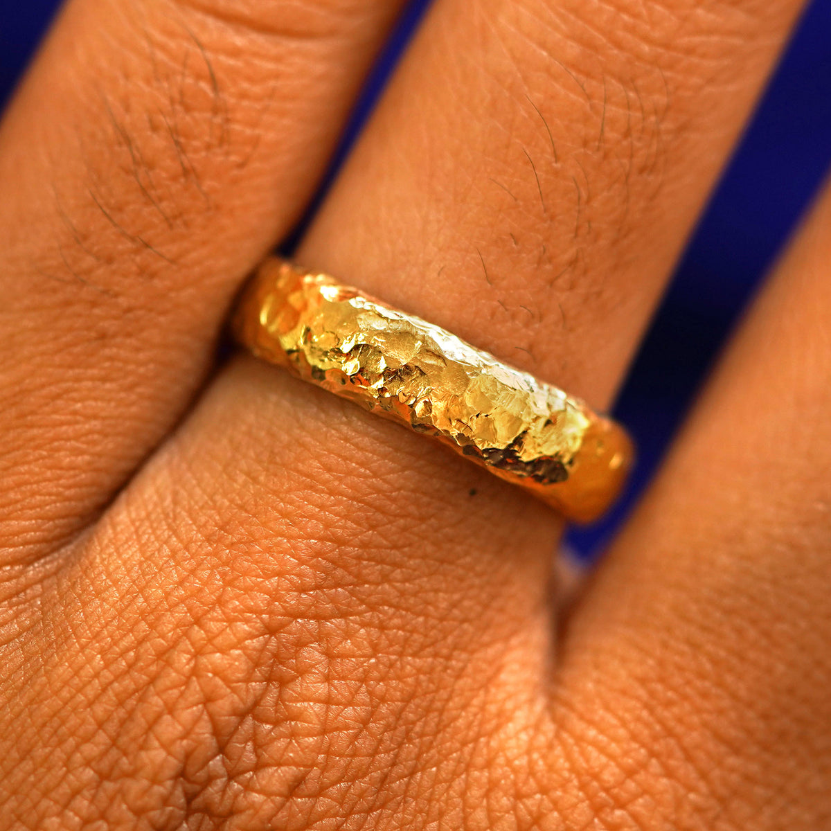 Close up view of a model's fingers wearing a 24k Band with a organic finish