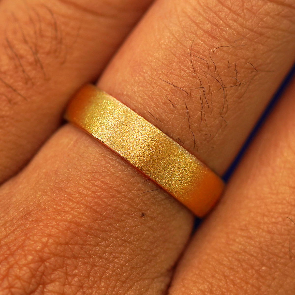Close up view of a model's fingers wearing a 24k Band with a stardust finish