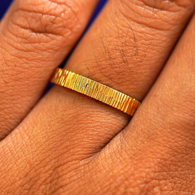 Close up view of a model's fingers wearing a 24k Band with a wood finish