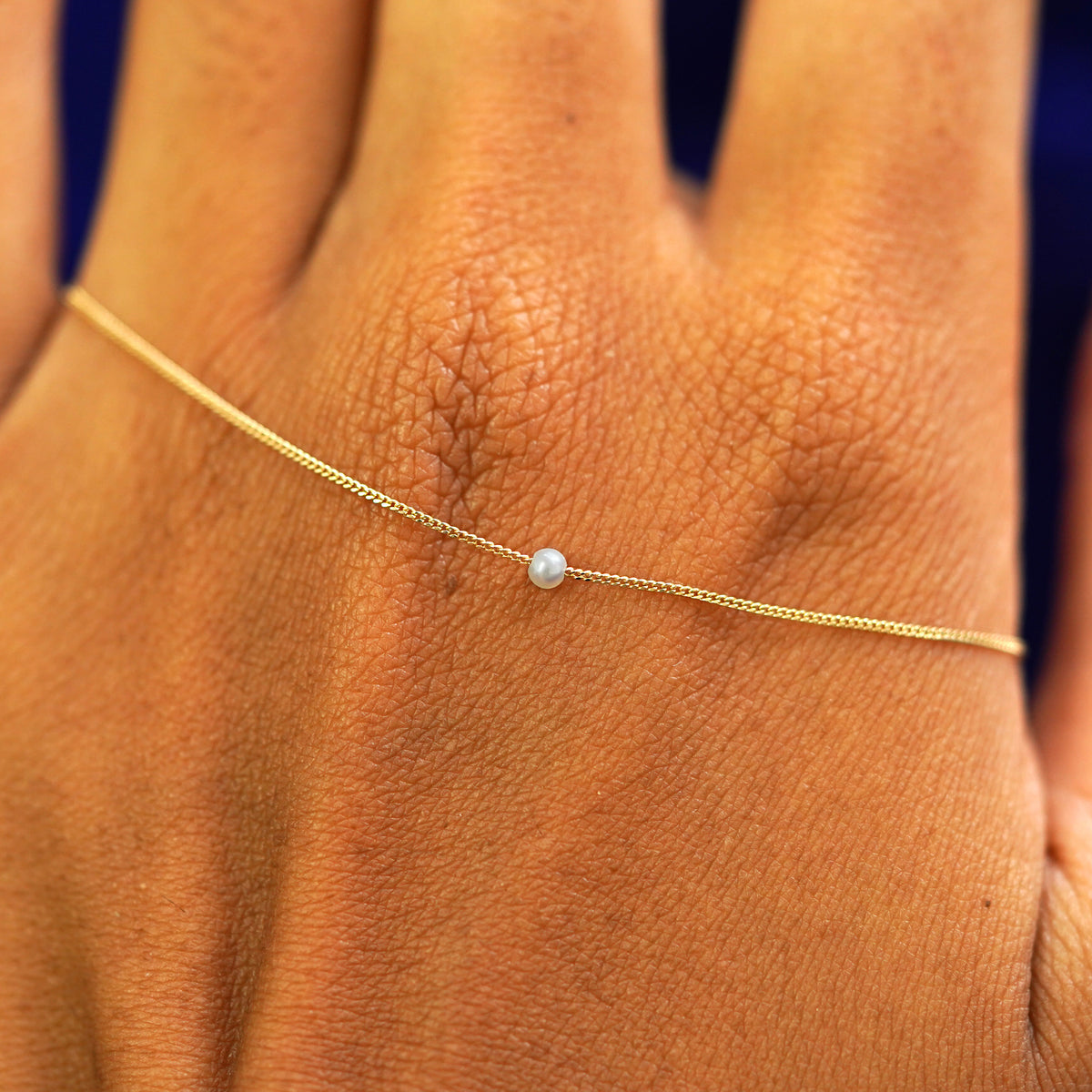 A 2mm pearl slide necklace resting on the back of a model's hand