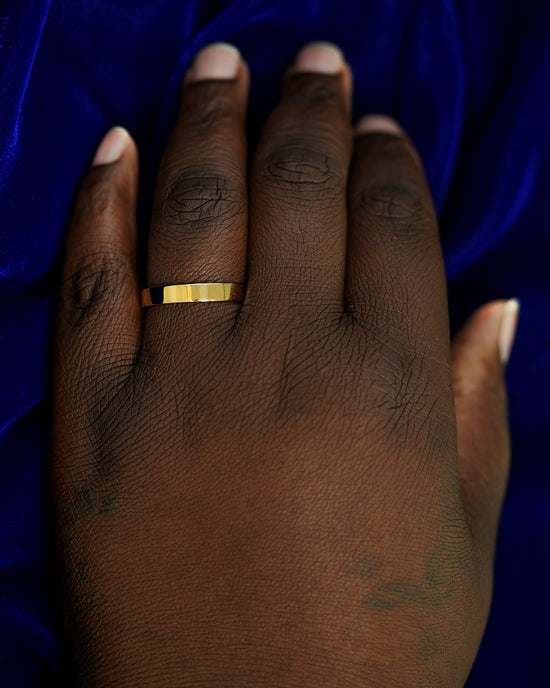 A hand wearing a 4mm band in size 14