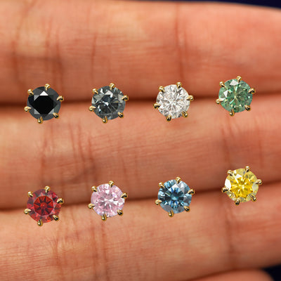Eight versions of the 5mm Moissanite Earring in between a model's fingers in all the gem color options