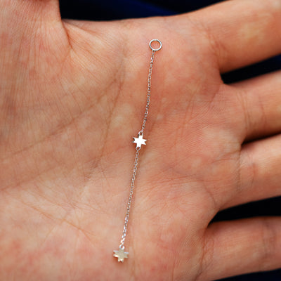 An 8 pointed star extender earring laying flat in a models hand to show the length of the extender