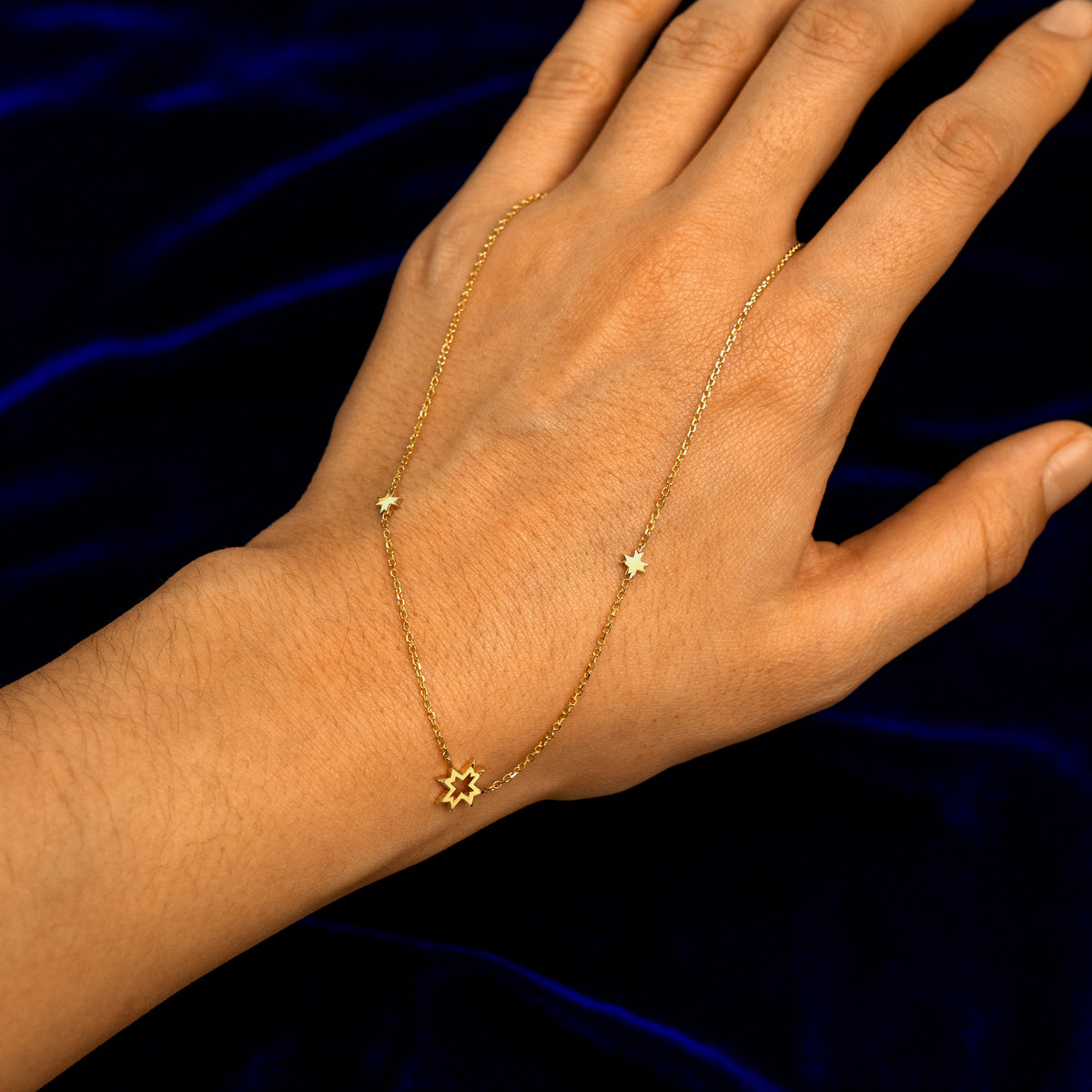 A model showing the full design of an 8 pointed star necklace by wearing it on the back of their hand
