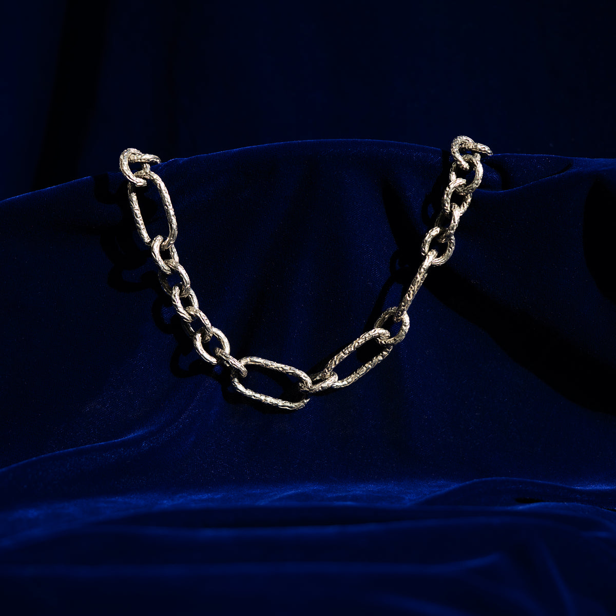 A photo of a silver chunky chain on a blue background