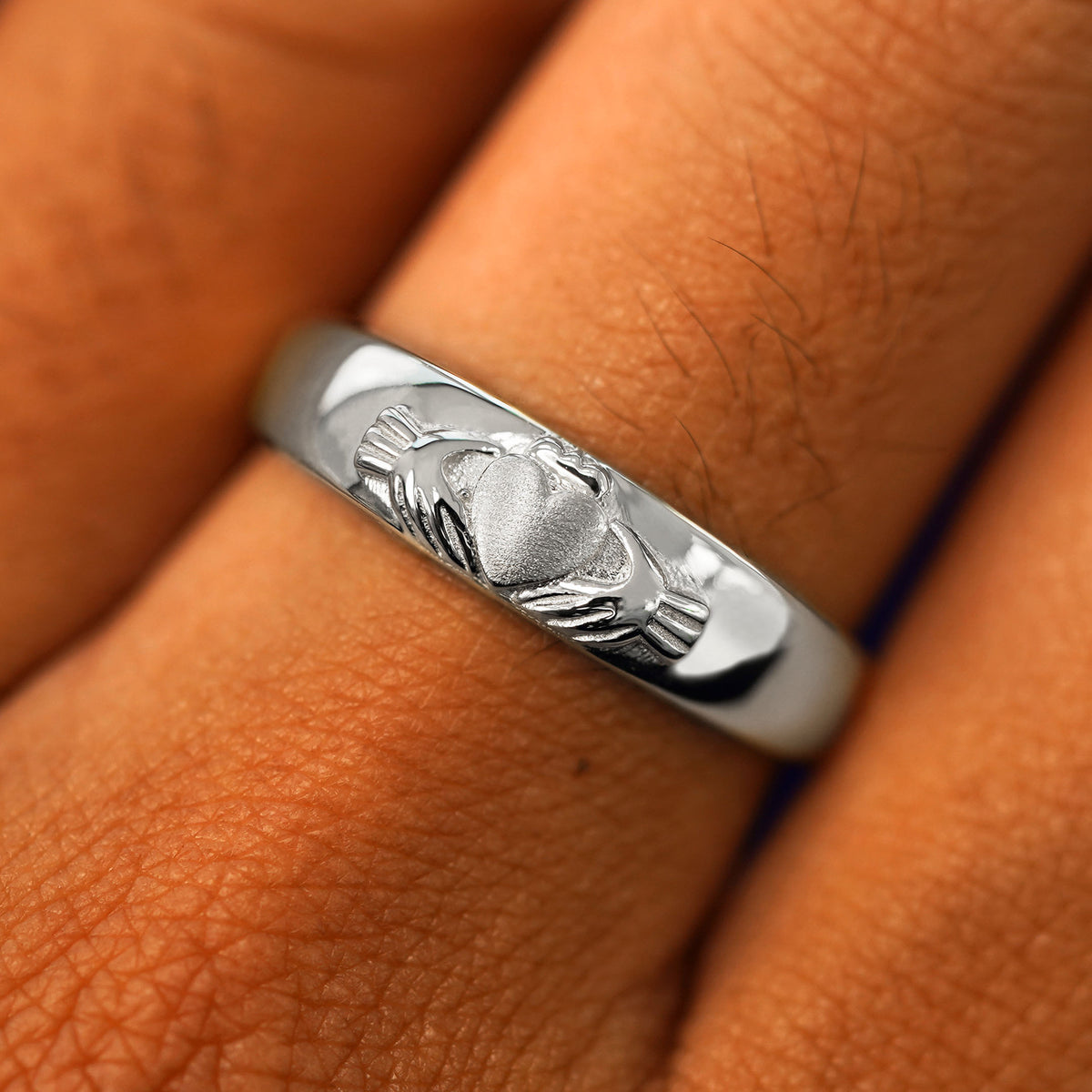 Close up view of a model's fingers wearing a 925 sterling silver Claddagh Band