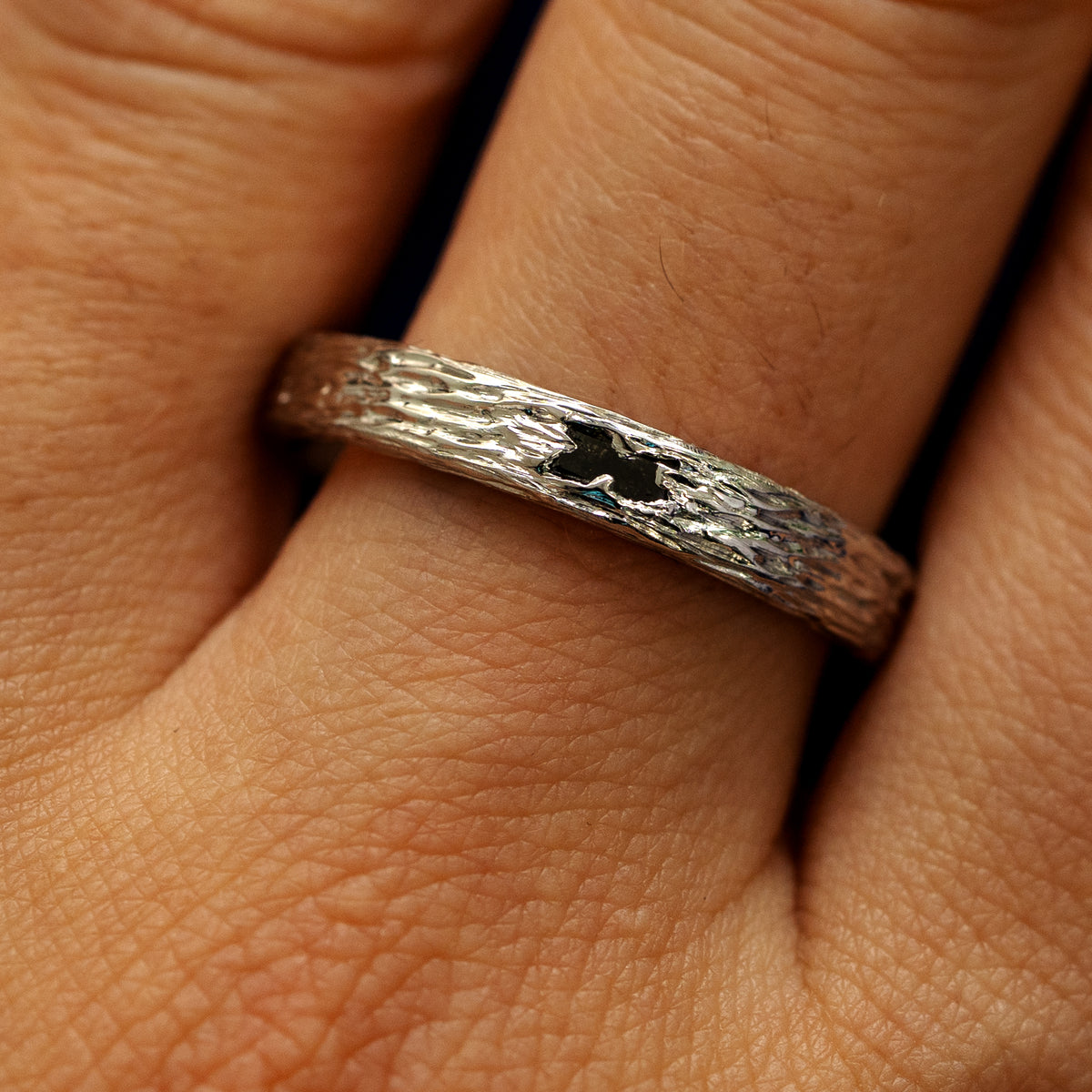 Close up view of a models fingers wearing a 950 platinum baguette diamond raw band