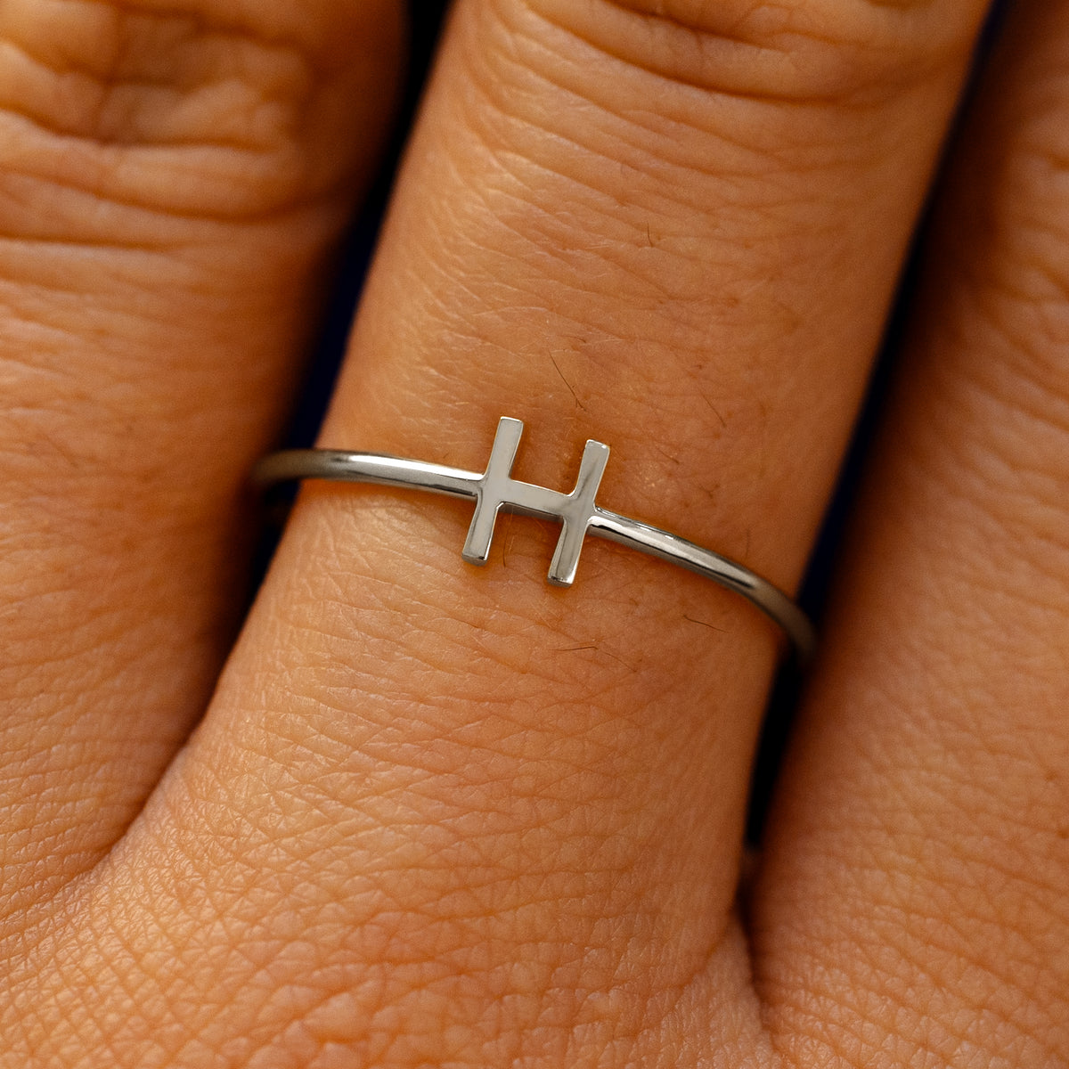 Close up view of a model's fingers wearing a 950 platinum block initial Ring with the letter H