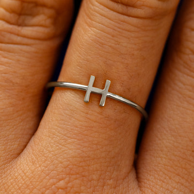 Close up view of a model's fingers wearing a 950 platinum block initial Ring with the letter H