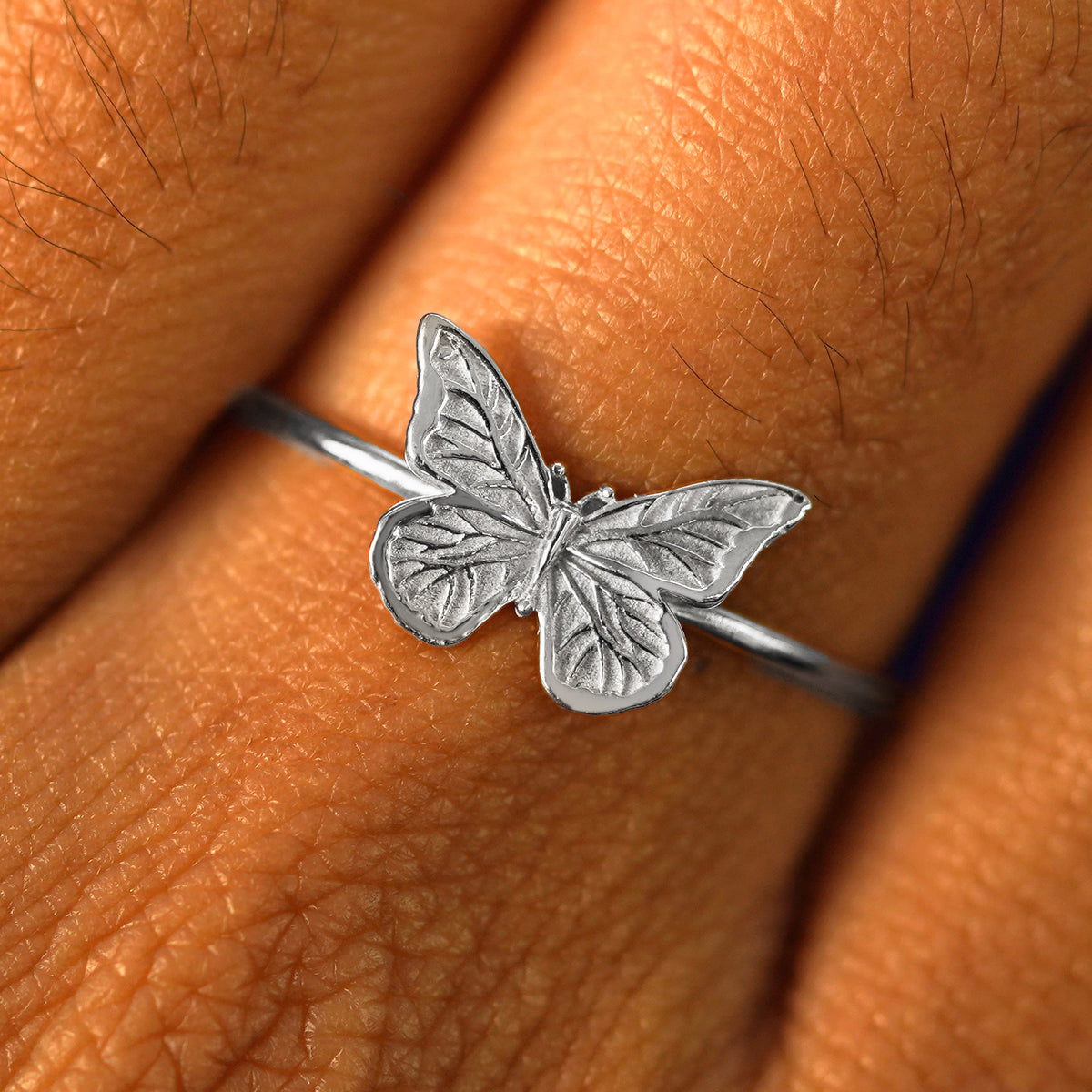 Close up view of a model's fingers wearing a platinum Butterfly Ring