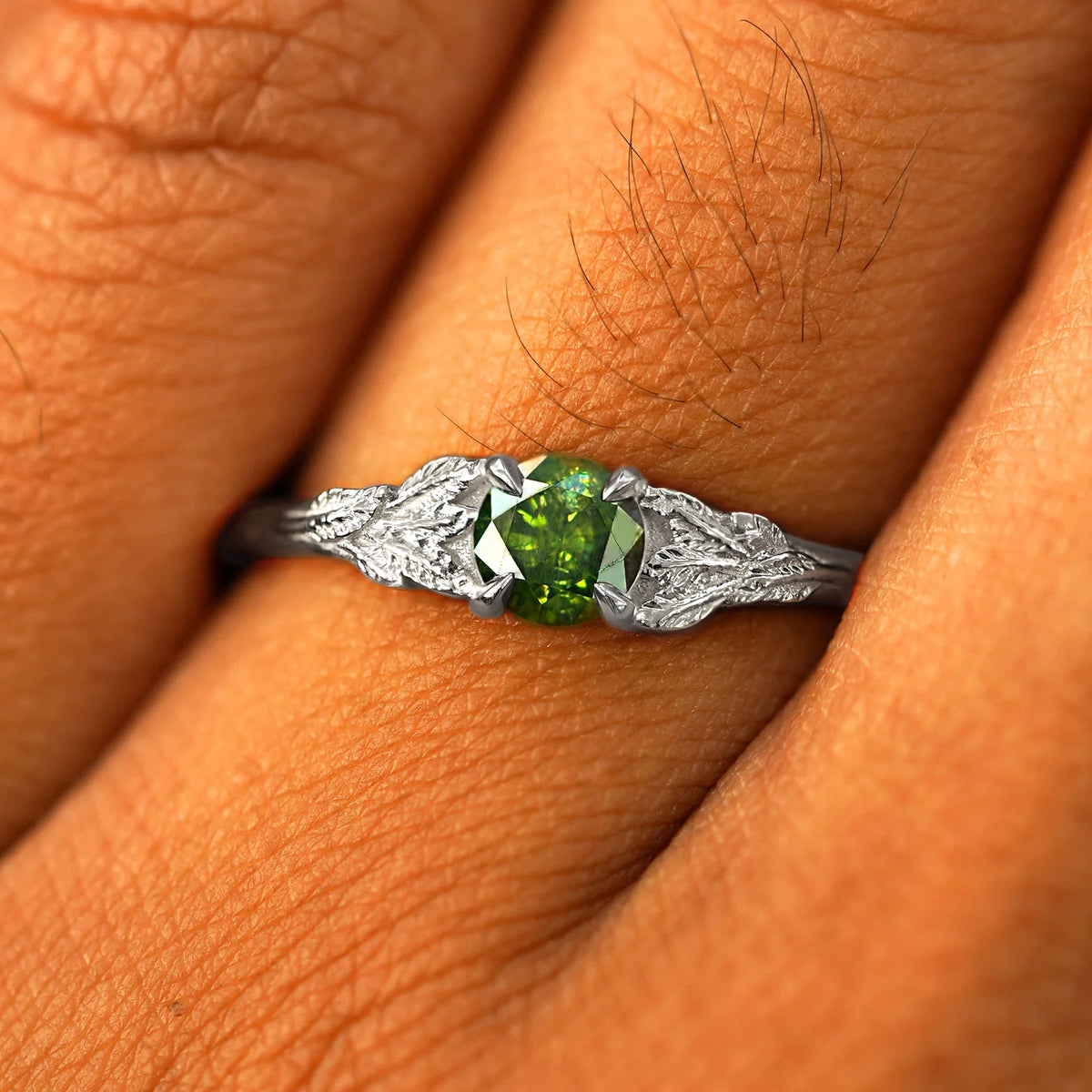 Close up view of a model's fingers wearing a 950 platinum Green Diamond Leaves Ring