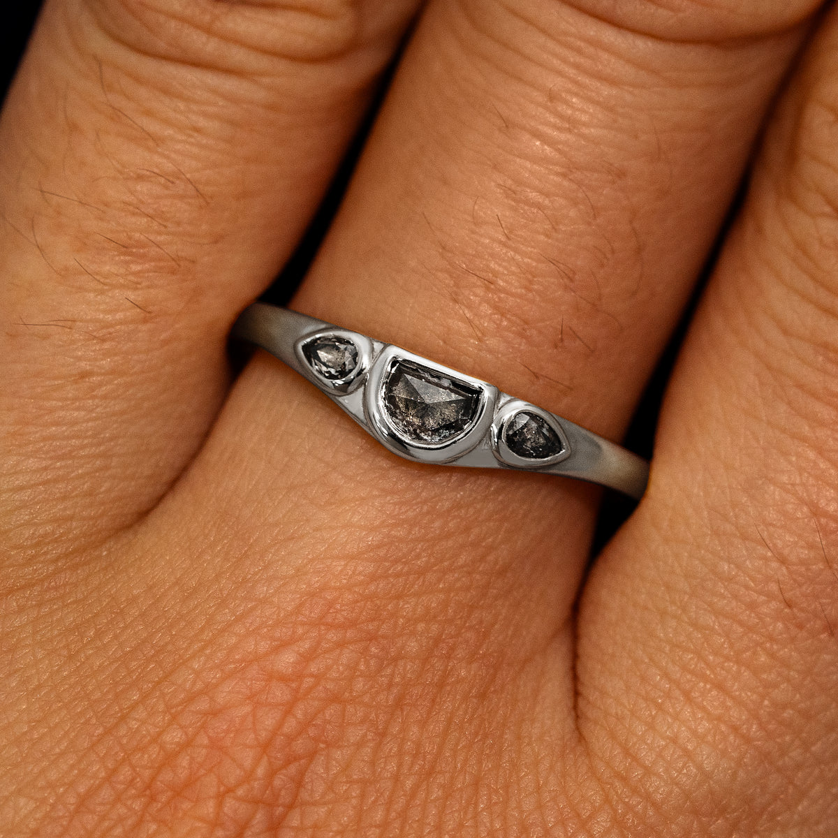 A model's hand wearing a 950 platinum Moon Cut Salt and Pepper Diamond Ring