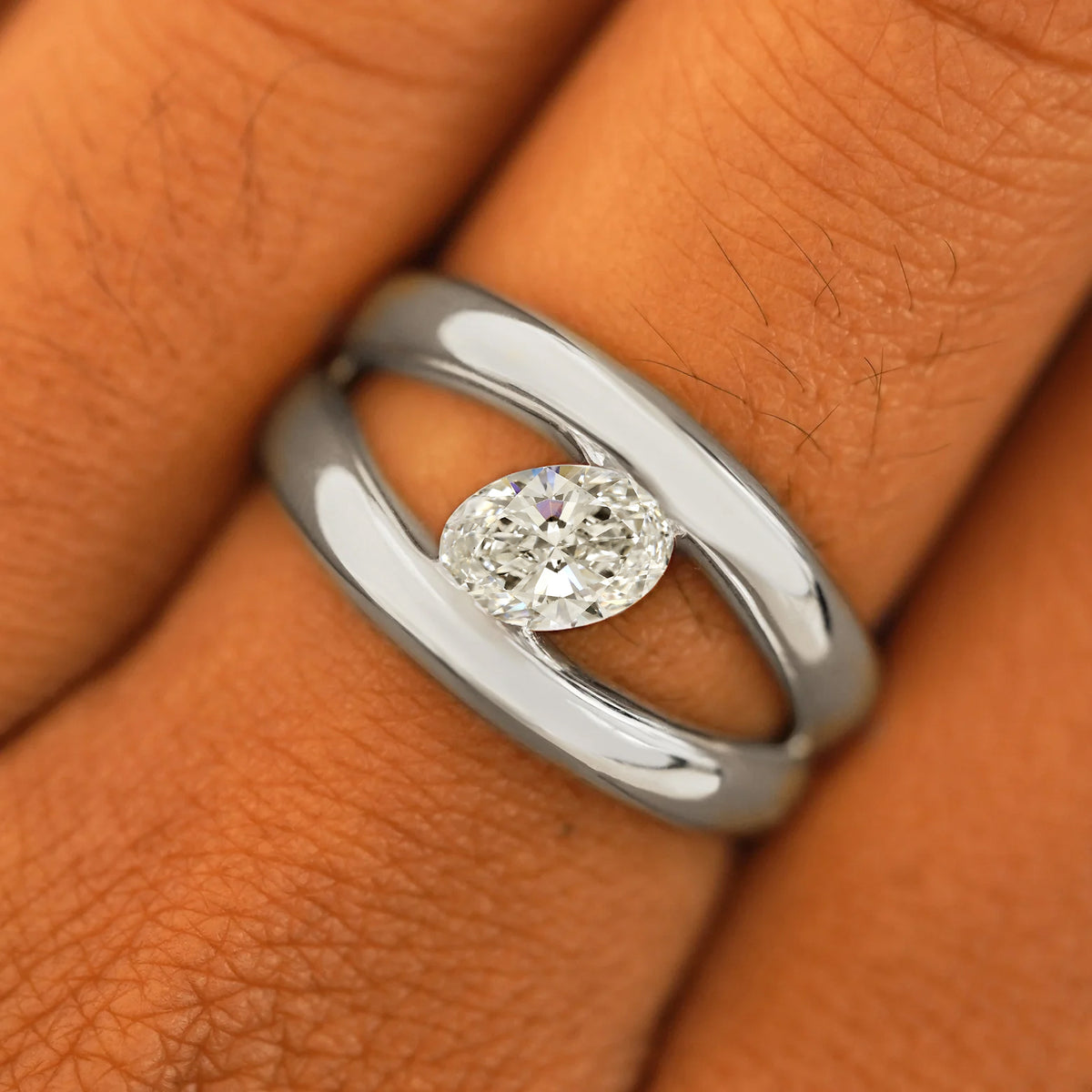 Close up view of a model's fingers wearing a 950 patinum Oval Lab Diamond Tension Ring