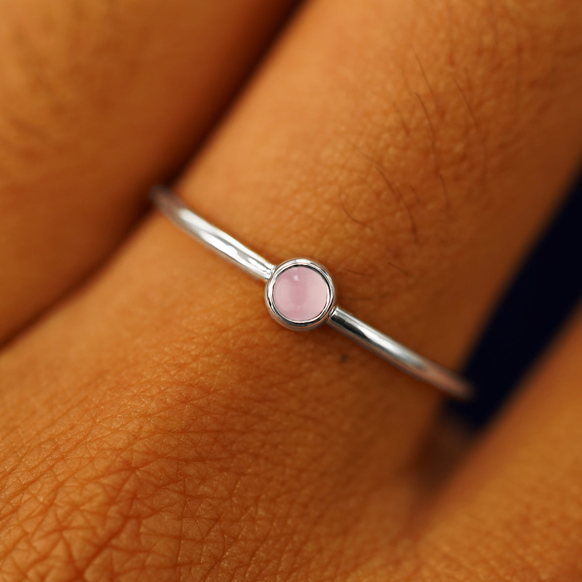Close up view of a model's hand wearing a platinum Rose Quartz Ring