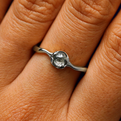 Close up view of a model's hand wearing a 950 platinum round cabochon salt and pepper diamond ring