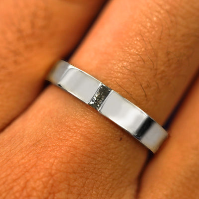 Close up view of a model's hand wearing a solid platinum Salt and Pepper Baguette Diamond Band