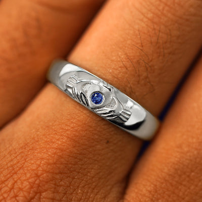 Close up view of a model's fingers wearing a 950 platinum sapphire Gemstone Claddagh Band