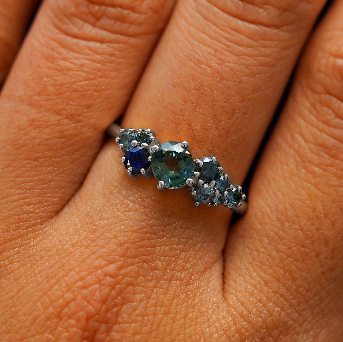 Close up view of a model's hand wearing a 950 platinum sapphire cluster ring