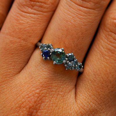 Close up view of a model's hand wearing a 950 platinum sapphire cluster ring
