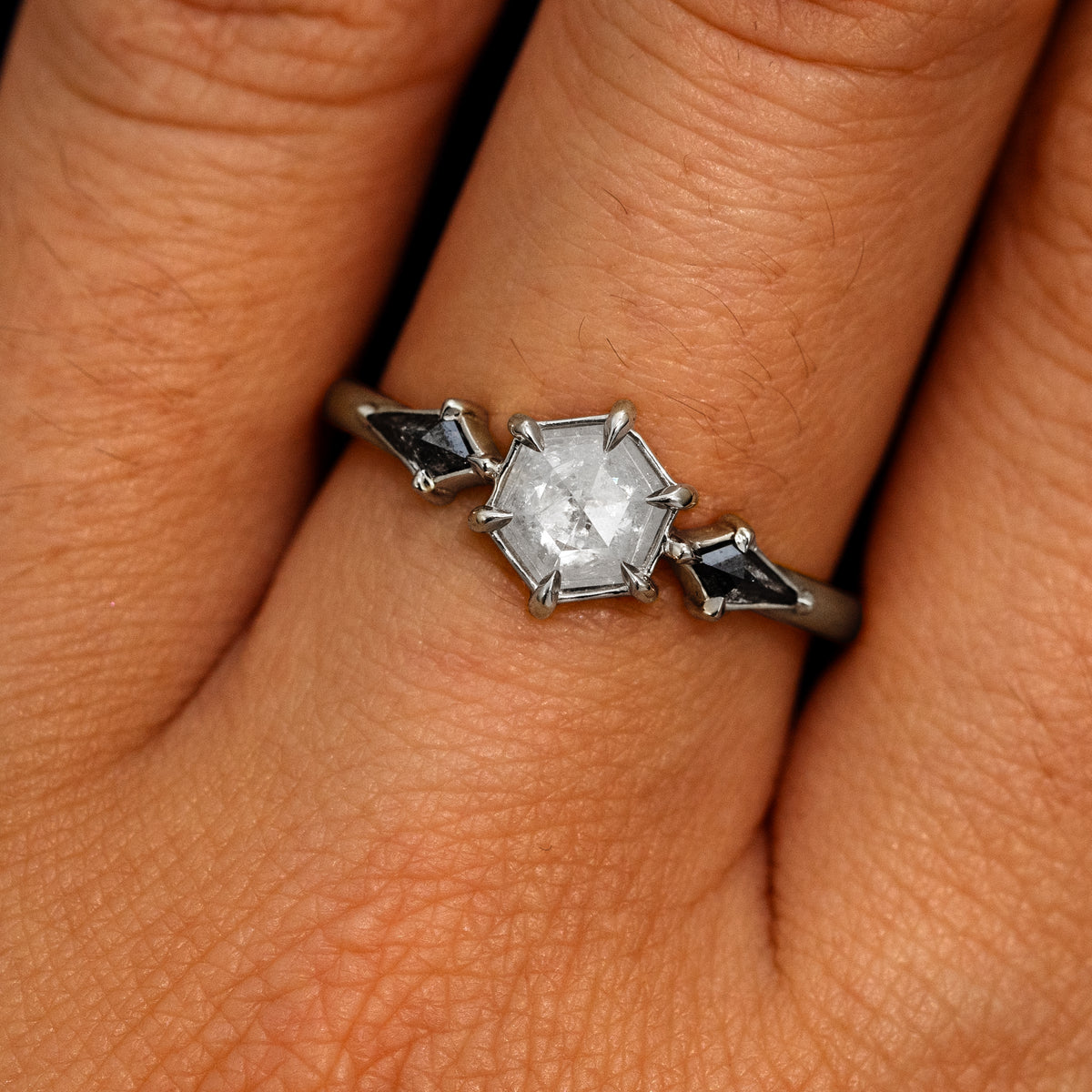 A model's hand wearing a 950 platinum Hexagon Salt and Pepper Diamond Black and White Ring